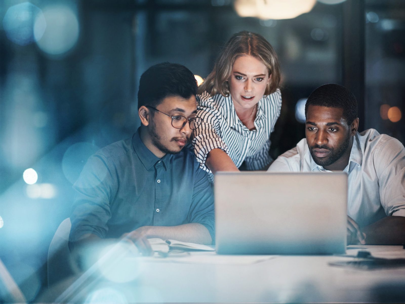 Cropped shot of three young businessmpeople working together on a laptop in their office late at night Showing them the way
